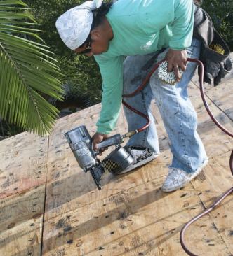 After the roof has been scraped clean, the crew renails the sheathing to meet new high-wind codes.