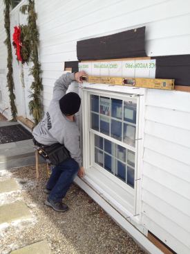 Before screwing the window trim into place, Manny adds spacers to hold the trim level.