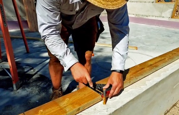 To align mudsill with anchor bolts, the author places the board against the bolts and marks each one.