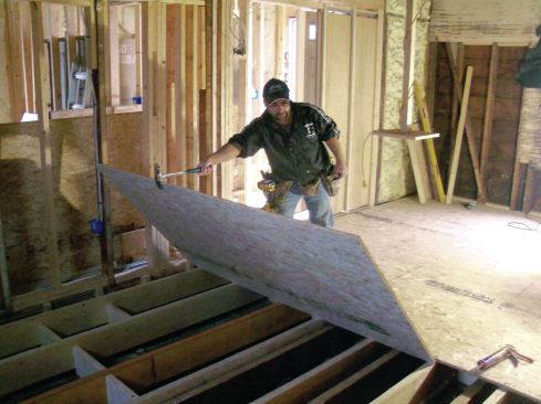 Finally, I insulated the ends of each joist bay against the outside wall with fiberglass batts. To complete the floor system, I glued and screwed 3/4-inch OSB subfloor to the joists, staggering the end seams as I went along (18). In the end, the extra time I spent paid off. The floor was completely flat, level, and solid as a rock—a perfect foundation for the new kitchen cabinets.