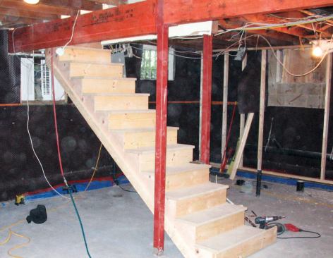 After the 4-inch concrete slab was poured, we framed 2x4 walls around the perimeter, placing them far enough in from the block walls to clear the steps in the new footings.