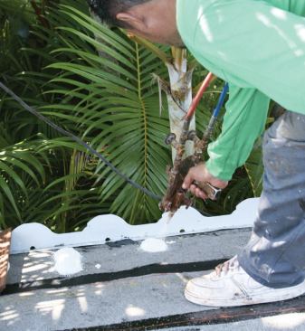 At roof edges, the crew attaches the cement tiles using redundant methods: First, a thick dab of two-part polyurethane adhesive foam.