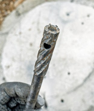 Drill-in anchors depend on your being able to predrill through concrete and rebar. One option is a small core drill. Going this route, you have to start out with a regular carbide bit for concrete, and as soon as you hit rebar, switch to a core bit like the one pictured here ... and then switch back to the concrete bit as soon as you are are clear of the rebar. It's slow going, to state the obvious.