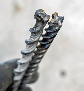 Left: A standard 2-point carbide rotary-hammer bit for drilling concrete only. Right: A 4-point carbide Diablo Rebar Demon, which drills through both the concrete and the rebar. What typically kills a standard bit when up against rebar is the heat generated from hammering on the steel. The Diablo got plenty hot during use; you can see that the shank of this Diablo has turned blue. But it could take it and continued to cut through concrete and steel.