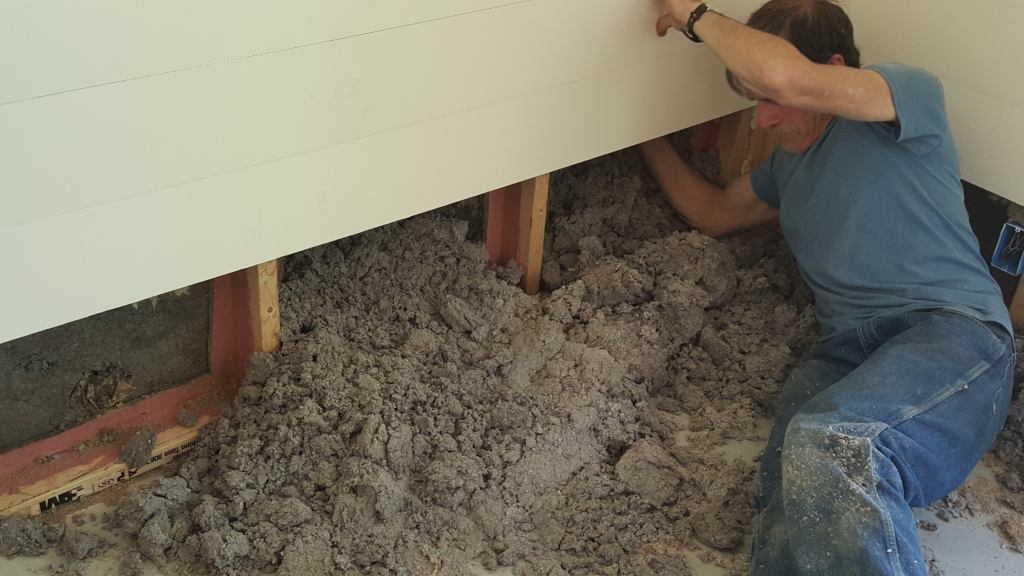 The overnight plumbing break flooded the newly built Passive House with more than a foot of water, some of which was able to seep into the outer insulated cavity of EcoCor's double wall system. Here, a worker pulls damp insulation out of the outer wall from inside the house.