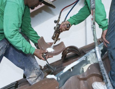 The roofers apply foam adhesive to the channel, as well as to the tile.