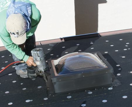 The skylight is set into the tar and secured with ring-shank nails.