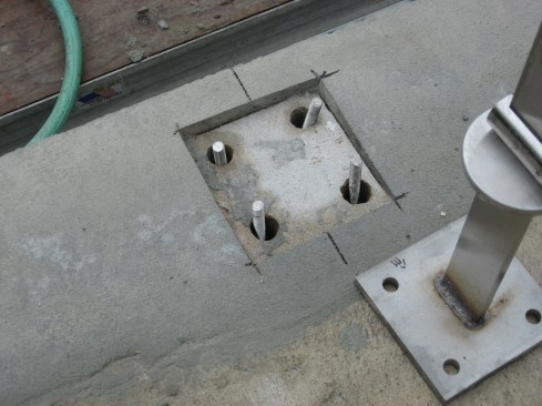 Preinstalled posts. The bases of these posts for glass railings needed to be bolted to the masonry deck.