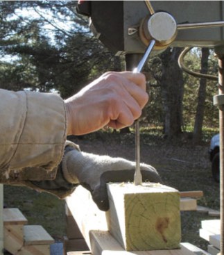 A small drill press set up with a plank to support the posts makes for fast, accurate, and nearly effortless boring.