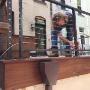 Water drains from the deck through a large scupper in the curb and runs through a custom-fabricated leader head. The powder-coated aluminum deck railing is also custom-fabricated.