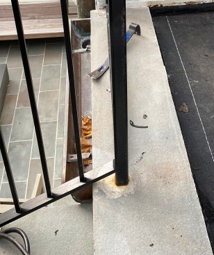 A railing subcontractor  drilled through the waterproofing layer when setting this post base.