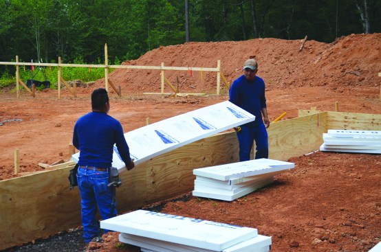 The crew set R-Tech Type IV polystyrene insulation in the bottom of the footing trenches.
