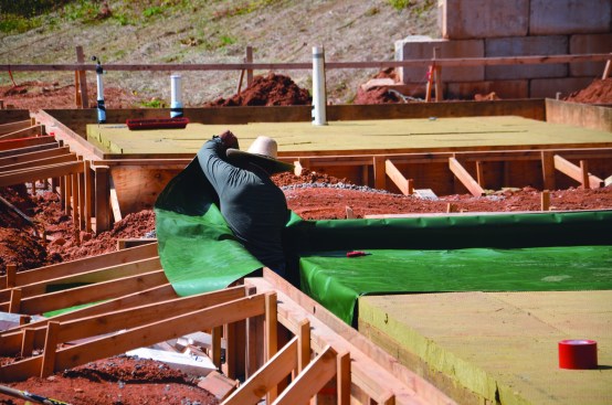 The crew placed a 15-mil polyolefin vapor barrier (Perminator from WR Meadows) across the slab and down into and up out of the footing trench.