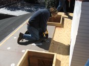 A roofer screws down tapered foam insulation from a "roof kit" while preparing the deck for a membrane roof. Sloped roof kits don't cost much more than ordinary insulation, so they're a cost-effective way to achieve the appropriate slope.