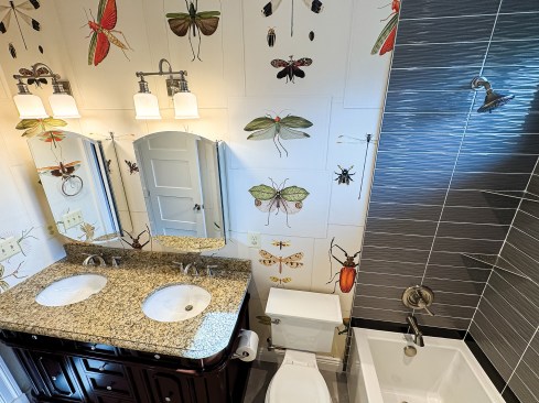 The second-floor bath features dramatic wallpaper that offers a fun, modern take on ornate Victorian style.