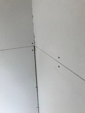 Any large crack (over 1/8-inch) or void needs to be filled with a setting compound. This prefill should cure before taping.