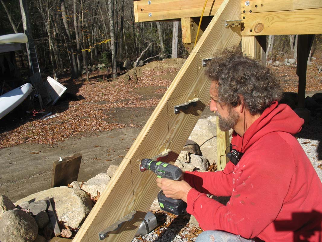 After setting the brackets, pilot holes are drilled for structural screws to be driven through the outside of the stringers and into the end of the treads to help keep the assembly tight. 