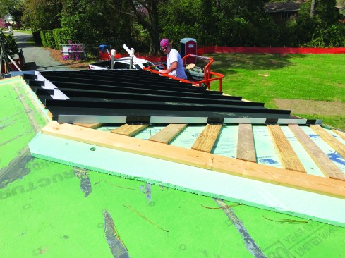 The crew tested a standing-seam roof installation over sleepers, rigid foam, and sheathing.