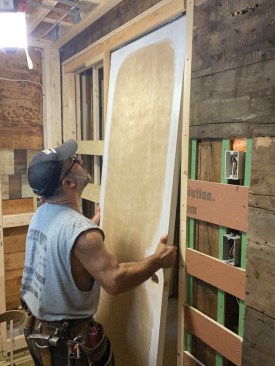 He primed and painted all four edges of the door before installing the mounting hardware and hanging the door from the track.
