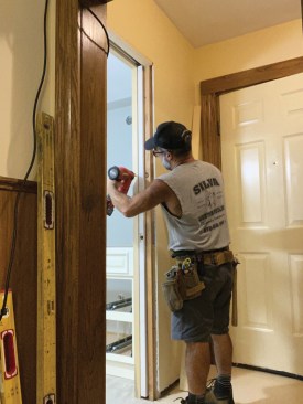After installing the strike jamb and the drywall, the author used 18-gauge brads to fasten the trim to the split jamb.