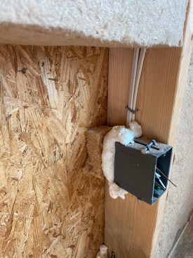 A portion of the cut-out is fit behind the electrical box. 