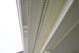 We cut saw kerfs into the edges of our soffit boards, and slip the flanges of the metal strip vents into these kerfs.