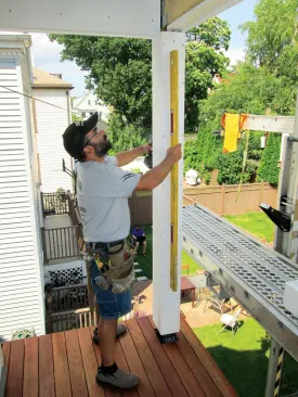 I slide the sleeve up as high as it can go and drive screws on all sides at the bottom, securing it with a space between the sleeve and the post. Next I plumb the sleeve in both directions and drive screws near the top to anchor it. At this point I can use my screws to micro-adjust the sleeve for plumb.