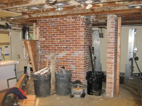 The obstacle to creating a new, larger media room and custom wine cellar was the massive base of a brick chimney. The chimney base needed to be removed, and our job was to support the upper portion of the chimney and flues--which were to remain--with steel beams.