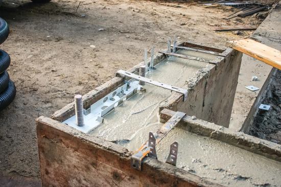 The author prefers Simpson MASA mudsill anchors over traditional anchor bolts for fastening the framing to the foundation. In the rush of the pour, this shear brace template was installed upside-down, so the author will just pop it out after the concrete has set up.
