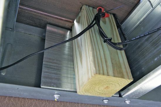 Wood posts are bolted to the steel framing. A short piece of track between the joist and the post stiffens the joist and provides a rigid mounting surface.